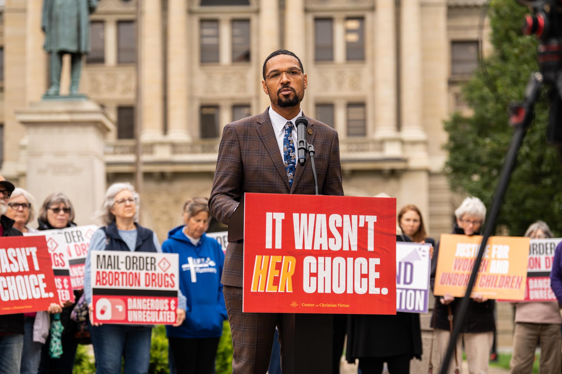 A speaker at the podium in front of the Lucas County Courthouse