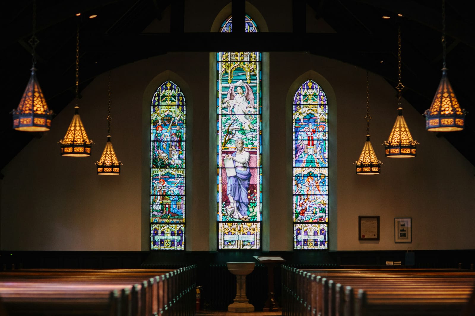 Church sanctuary with stained glass windows and hanging lights